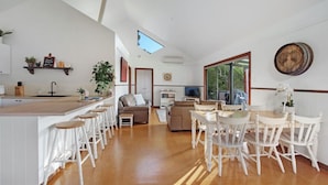 Amplia sala de estar con cocina, mesa de comedor y taburetes de bar.