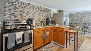 A modern kitchen with wooden cabinets, a stainless steel refrigerator, and a built-in microwave. - C & N Lodging, Bluffton, SC (Bluffton)