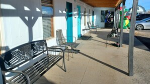 Un espacio al aire libre techado con un banco, sillas y una máquina expendedora.