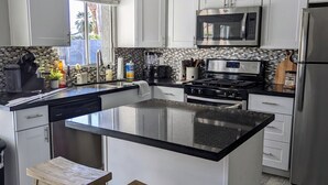 A modern kitchen with white cabinets, a black countertop, a stainless steel refrigerator, and a built-in microwave. - Scottsdale Kierland Mayo Clinic Desert Ridge (Phoenix)