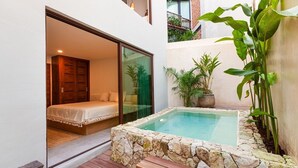 A modern bedroom with a glass door leading to a balcony, a small hot tub, and potted plants. - Azalea 5 Condos 8BR 23 PPL  Private Pool (Tulum)