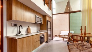 A modern kitchen with wooden cabinets, a microwave, and a refrigerator. There is a dining area with a table and chairs. - Azalea 5 Condos 8BR 23 PPL  Private Pool (Tulum)