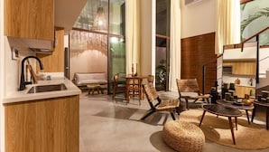 A modern living room with a kitchen area, large windows, and a staircase. - Azalea 5 Condos 8BR 23 PPL  Private Pool (Tulum)