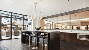 Una cocina moderna con una isla central, taburetes de bar y un ventanal con vistas al exterior.