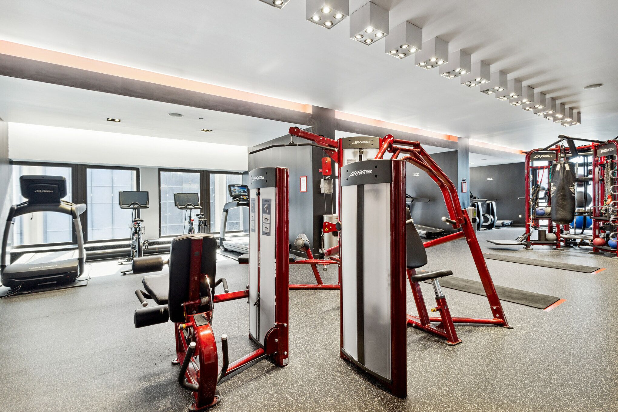 Un gimnasio moderno con diverso equipo de ejercicio, amplias ventanas y un diseño espacioso.