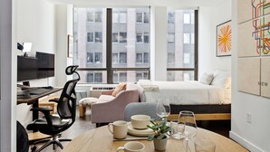 Una habitación de hotel moderna con cama, escritorio, ordenador y zona de estar.
