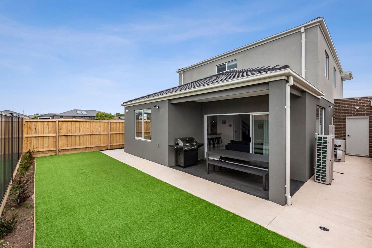 A modern house with a covered patio, a barbecue area, and a well-maintained lawn.