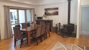 A dining area with a wooden table and chairs, a painting on the wall, and a fireplace.