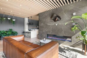 Relax in a stylish seating area with a leather sofa, fireplace, and modern kitchen.