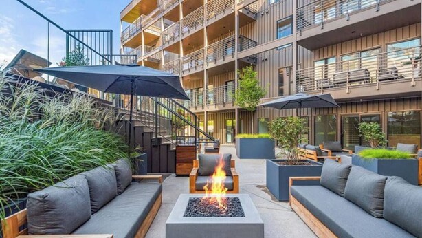 An outdoor seating area with sofas, a fire pit, and umbrellas. - 3BR/2BA Lux Condo | Pool |Walk to Broadway (0.8mi) (Nashville)