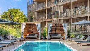 A modern hotel with a rooftop pool, outdoor seating, and a multi-story building with balconies. - 3BR/2BA Lux Condo | Pool |Walk to Broadway (0.8mi) (Nashville)