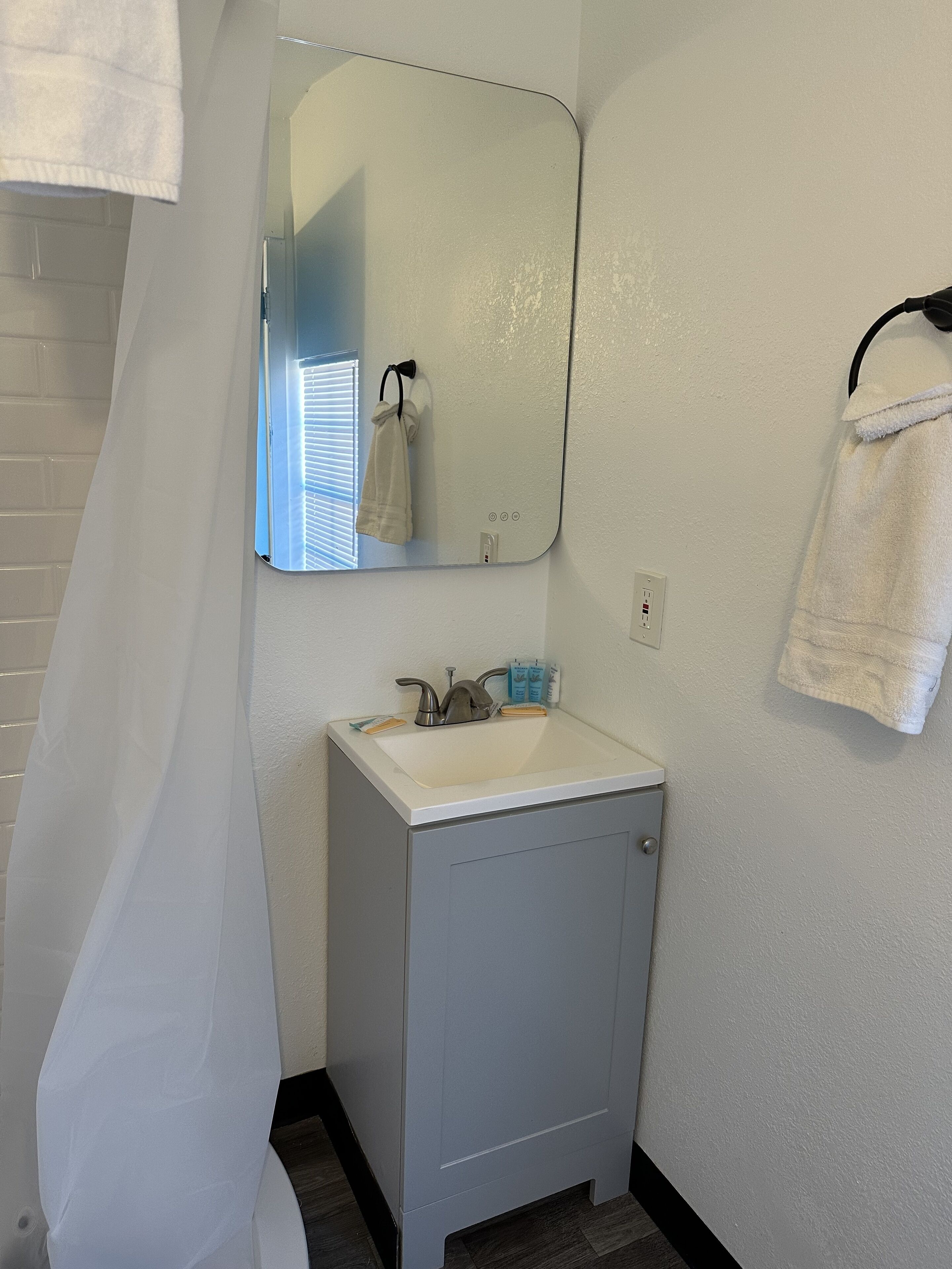 Une salle de bain avec un lavabo blanc, un miroir et un porte-serviettes.