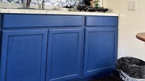 Una cocina con gabinetes azules, un salpicadero con diseño y una estufa negra.