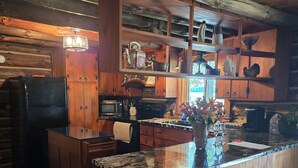 Une cuisine rustique avec des meubles en bois, un plan de travail en granit et un îlot central intégré.