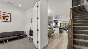 A modern interior with a grey sofa, a staircase, and a kitchen area. - Large 5BR w fireplace near NAU, Snowbowl! (Flagstaff)