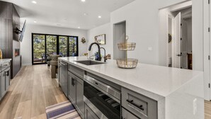 A modern kitchen with a large island, stainless steel appliances, and a view to the outdoors. - Large 5BR w fireplace near NAU, Snowbowl! (Flagstaff)