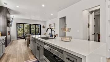 A modern kitchen with a large island, stainless steel appliances, and a view to the outdoors.