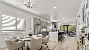 A modern kitchen with a central island, stainless steel appliances, and a dining area with a round table and chairs. - Large 5BR w fireplace near NAU, Snowbowl! (Flagstaff)