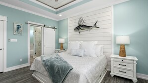 A bedroom with a bed, nightstands, a wall-mounted fish decoration, and a door leading to a bathroom.