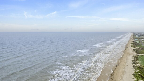 A coastal view with a sandy beach and ocean waves.