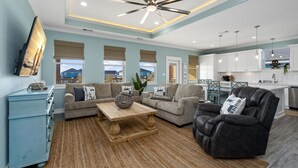 A spacious living room with a ceiling fan, a wooden coffee table, and a black leather recliner.
