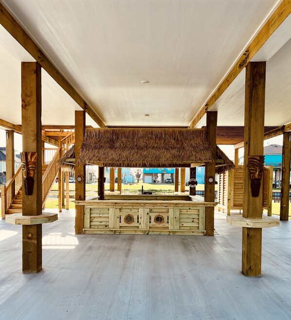 An open wooden structure with a central bar area and a thatched roof.