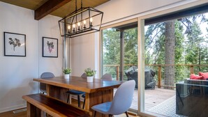 A modern dining area with a wooden table, chairs, and a hanging light fixture.