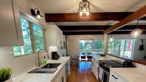 A modern kitchen with wooden flooring, white cabinetry, and a central island.