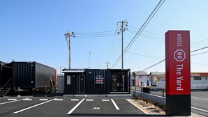 A hotel entrance with a red sign, a black container, and a clear sky. - HOTEL R9 The Yard Kurashiki (Kurashiki)