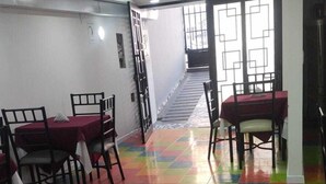 A room with a colorful checkered floor, two tables with chairs, and a staircase leading to an upper level. - Hotel Boutique FC (Bogotá)