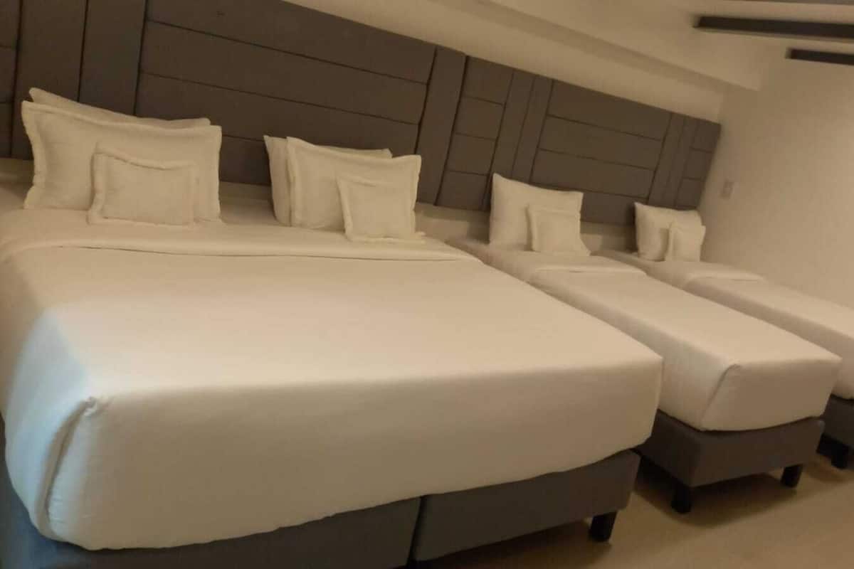 A hotel room with two large beds and two smaller beds.