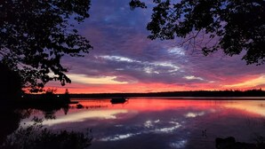 Een rustig meer bij zonsondergang, met bomen die het uitzicht omlijsten.