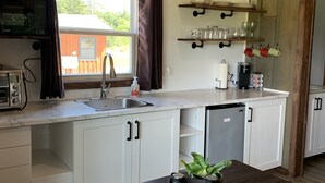 Een moderne keuken met witte kastjes, een donker houten tafel en een raam met gordijnen.