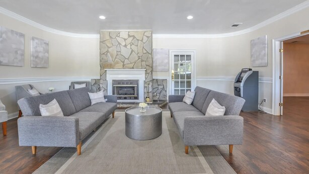 A spacious living room with two grey sofas, a round coffee table, and a stone accent wall. - Economy Hotel Macon    (Macon)