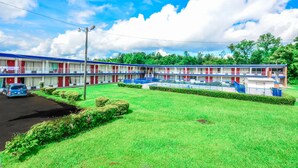 A motel with a row of rooms, a parking area, and a well-maintained lawn. - Economy Hotel Macon    (Macon)