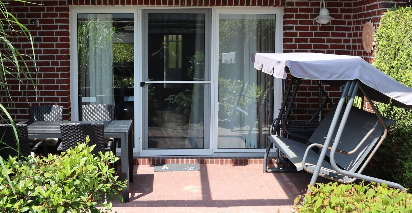 A patio with a table and chairs, a sliding glass door, and a small garden area.