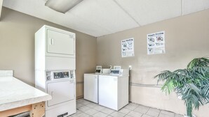 A laundry room with stacked washers and dryers, a table, and a potted plant. - Economy Hotel Atlanta   (Atlanta)