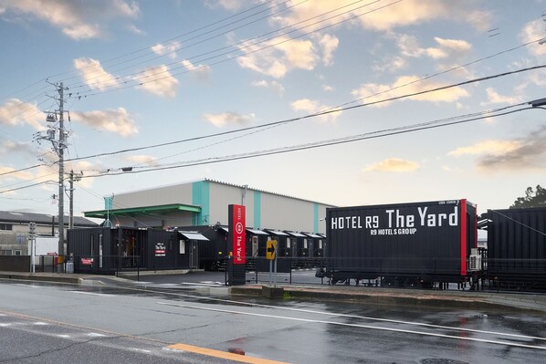 A hotel named "The Yard" with a large black container-like structure, a green awning, and a red sign. - HOTEL R9 The Yard Matsusaka (Matsusaka)