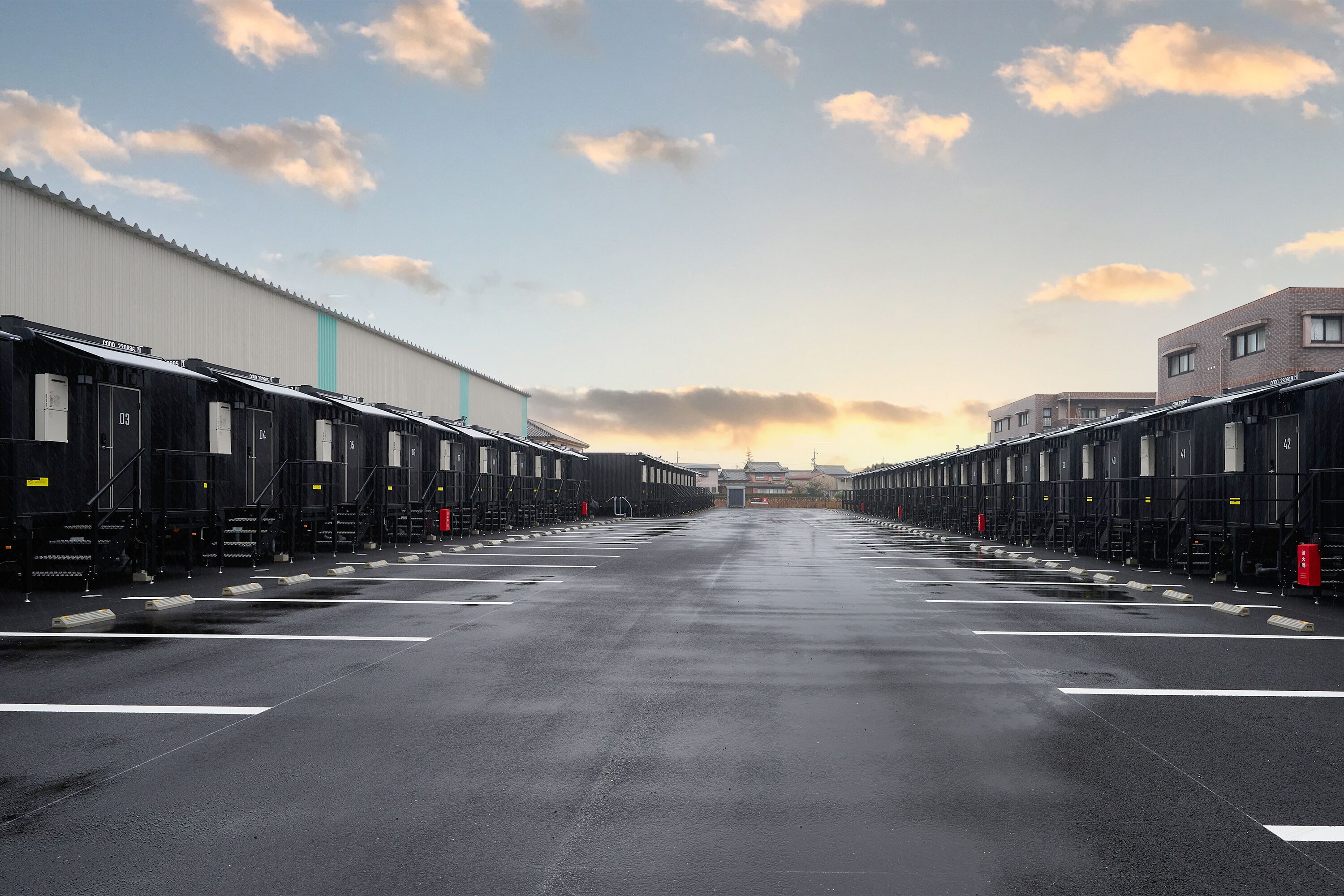 Un almacén industrial grande con filas de contenedores de transporte y un cielo despejado.