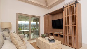 Un salon moderne avec un canapé, une table basse et un téléviseur posé sur un meuble en bois.