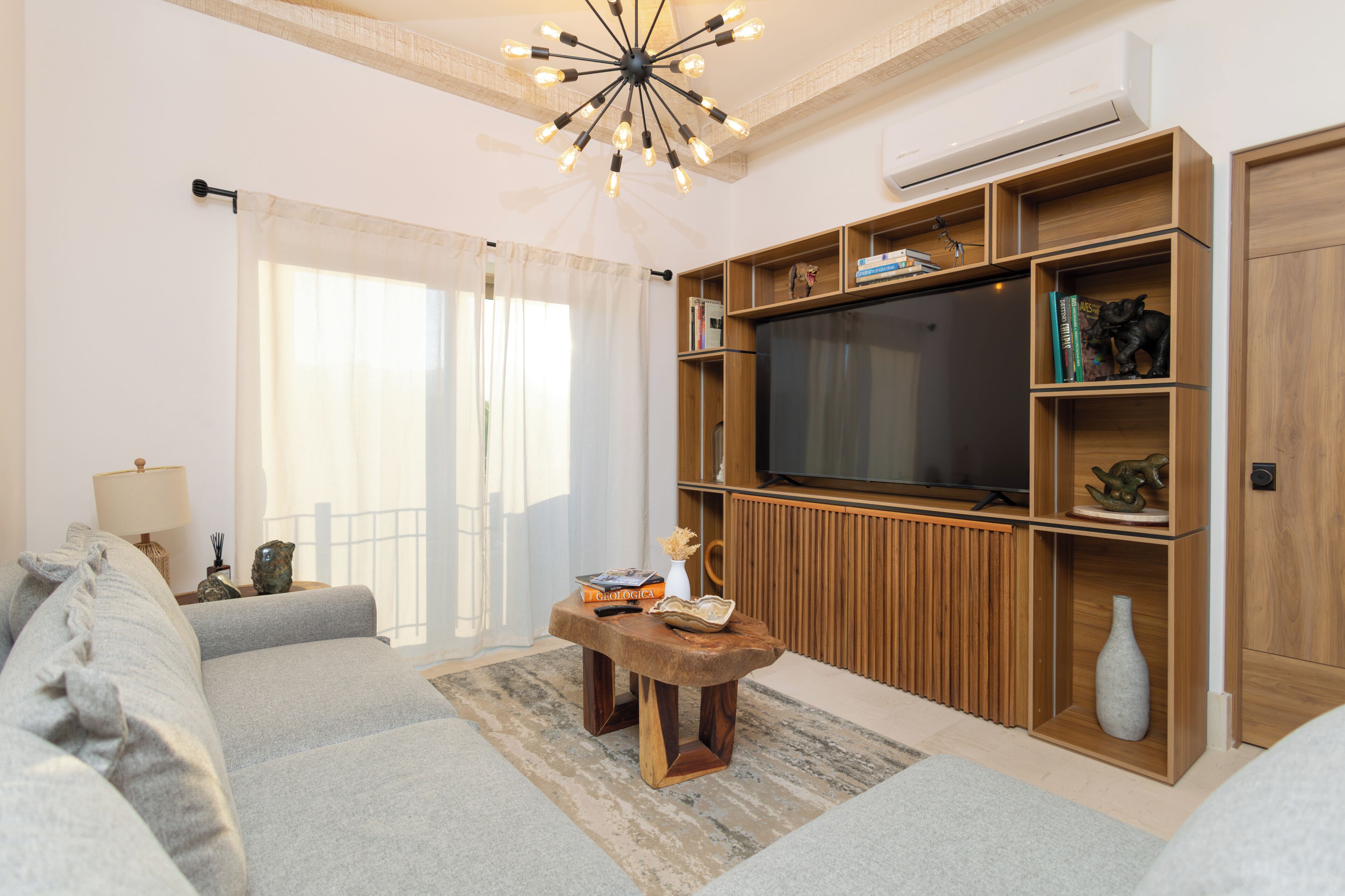 Una sala de estar con sofá, una mesa de centro de madera, televisor y estanterías empotradas.
