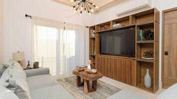Una sala de estar con sofá, una mesa de centro de madera, televisor y estanterías empotradas.