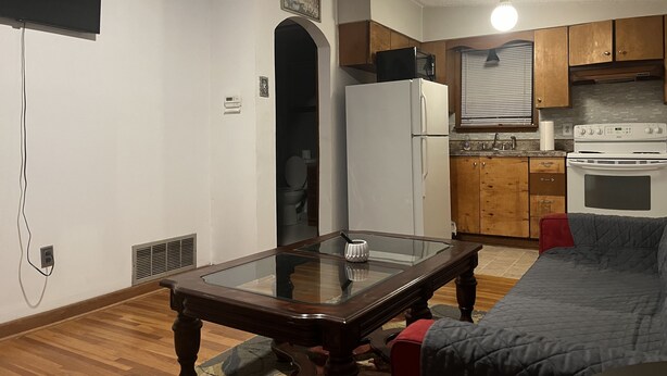 A compact living space with a kitchenette, a dining table, and a sofa.