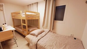A bunk bed room with a desk and a window.