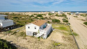 Ein Küstenhaus mit einer Terrasse und einem Sandstrand im Hintergrund.