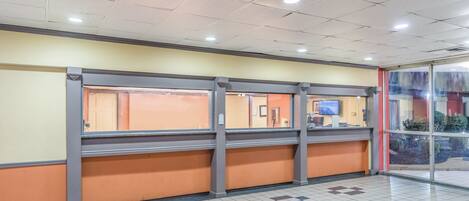 A reception area with a check-in counter, a seating area, and a glass door leading outside.
