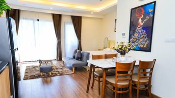 Une chambre d’hôtel moderne comprenant un coin repas, un canapé, une table avec des chaises et un tableau au mur.