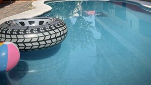 A swimming pool with inflatable toys and a clear blue water surface.