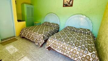 A room with two beds, a green wall, and a door.