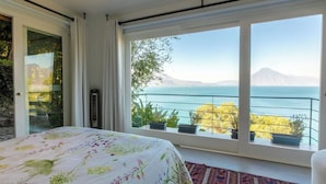 Un dormitorio con un ventanal que ofrece vistas a un lago y montañas.